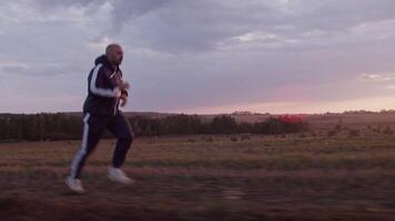 Sportsman jogging near field with haystacks in evening time video