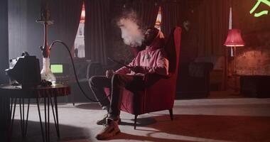 Lounging man with hookah and whiskey in bar video