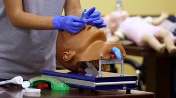 Medic shows how to insert oxygen tube in nose of a medical dummy. Competent doctor with nesessary instruments in hands. video