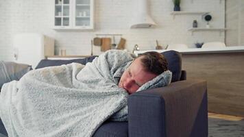Sick man under warm blanket on comfortable couch at home. Pandemic. Quarantine concept. video
