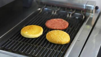 Fresh buns and raw cutlet are grilled on a barbeque. Selective focus on frying process. video