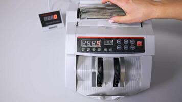 clerk hand counting dollars with electronic money counter machine at bank office or currency exchanger video