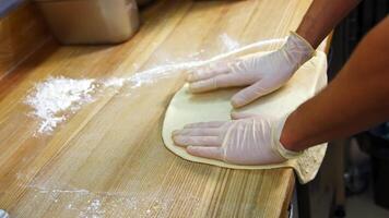 Chef forming the dough on a floured surface and kneading it with hands in a traditional pizzeria kitchen. Pizza maker prepares the dough for a tasty dish. video
