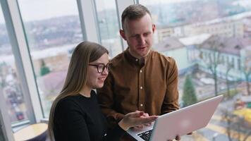 Young web designers look at laptop and discuss. Teamwork, coworking concepts. video