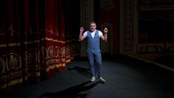 Man in front of empty theatre hall with red velvet chairs. Actor is standing on stage and talking with gestures before the performance. video