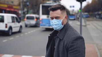 Man in protective medical wear looking to the camera walking in the city. Responsible behavior during world covid-19 pandemic. video