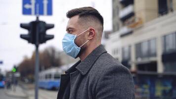 COVID-19. Man in city street wearing face protective mask against spreading coronavirus. Portrait of a male in coat and suit. video