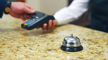 Guest makes card payment at check-in. Bell at hotel reception. Man in hotel lobby pay with nfc chip card. Blurred of payment with terminal during checking in. video