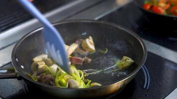 Mushrooms fried with vegetablesin a big frying pan. Chef turns fried ingredients with spatula. video