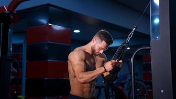 Man with perfect body train muscles on sport equipment. View from the side on handsome man with perfect body. video