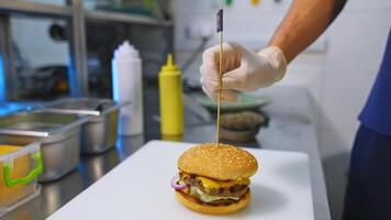 Fast food. Macro view of burgers, french fries, cola. Hands of a person make a hamburger from buns, cutlets, lettuce, cucumber, tomatoes, onions and sauces. Beautiful background. video