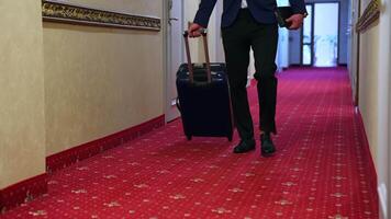 Unrecognizable businessman with luggage in a hotel corridor. A man with a suitcase is walking down a hotel hallway. video