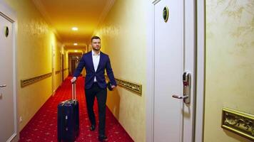 Man arrived to a hotel and is going to the room while pulling his suitcase through the lobby. video