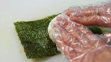 Chef in gloves is cookiing sushi. Sushi are made of rice, nori seaweed, cucumber, cream cheese. Appetizing and nutritious food concept. video