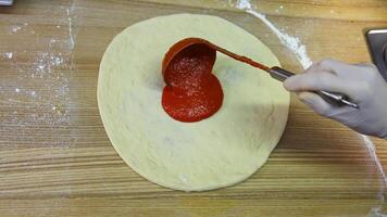 Chef spreading tomato sauce on pizza dough with ladle. Traditional pizza restaurant. Food footage. Close-up. video