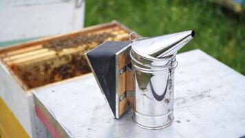 Selective focus on steel new beesmoker on the top of a hive. Hardworking bees fly over hives. video