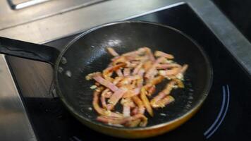 Frying bacon pieces in a pan. Crispy pieces of delicious bacon are fried in a hot skillet. Unhealthy food. video