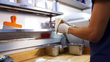 Restaurant chef is working. Hands are shaping floured dough for pizza. Experienced cooker making pizza using traditional recipe. Modern kitchen background. video