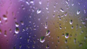 Water drops following down on window glass. Drops of rain trickling down isolated. Droplets running down. Colored background. video