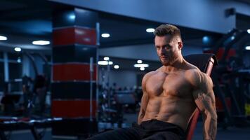 Shirtless young bodybuilder workout with dumbbells. Strong abs. Blue light filter. from the side. video