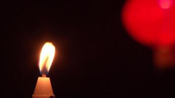 A single candle is lit in front of a red lantern video