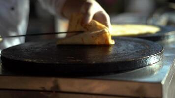 A baker folds a flatbread into a triangle on a stove video
