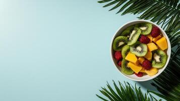 Fresh fruit salad with kiwi, mango, and raspberries in a bowl, tropical palm leaves background photo