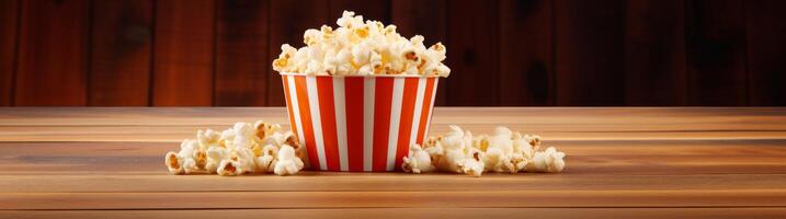 Delicious popcorn in a striped box on a wooden table photo