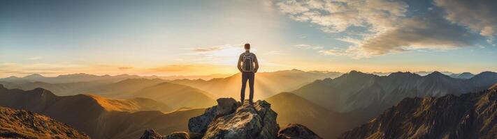 hiker standing on mountain peak at sunset photo