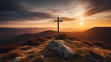 Silhouette of a cross on a hilltop at sunset photo