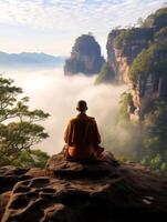 Serene monk meditating on rocky cliff overlooking misty mountains photo