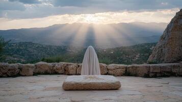 Ghostly figure on stone altar overlooking sunlit mountain range photo