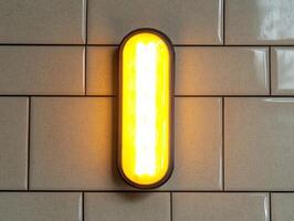 Illuminated rectangular wall light fixture on a beige tiled wall photo