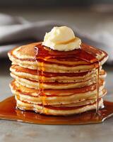 Stack of fluffy pancakes with butter and maple syrup photo