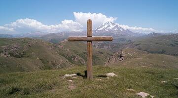 Wooden cross on a mountaintop with a snowy peak in the background photo
