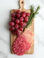 Charcuterie board with salami, prosciutto, grapes, and rosemary photo