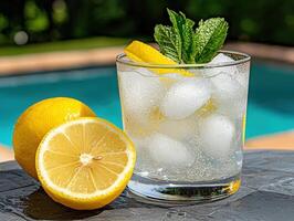 Refreshing summer lemonade with lemon slices and mint in a glass by the pool photo