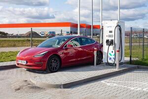 Kaunas, Lithuania - 12-10-2024 - Red Tesla Model 3 Dual Motor at the lithuanian charging station Ignitis ON photo