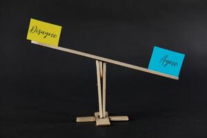 concept of duality using sticky notes with the antonym words Agree - Disagree made by hand on a dark background photo