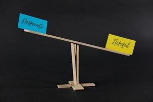 concept of duality using sticky notes with the antonym words Desperate - Hopeful made by hand on a dark background photo