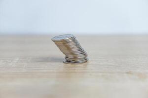 Stack of coins tilted on a table with a white background photo