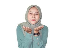 A smiling asian woman in a green hijab gestures playfully with her hands, radiating warmth and joy. photo