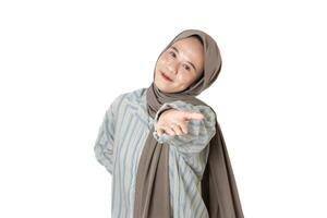 A woman wearing a hijab and a patterned blouse extends her hand and smiles warmly at the camera, inviting a connection or interaction. photo