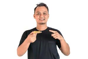 Happy Asian Man Pointing at a Delicious Slice of Pizza in Hand photo