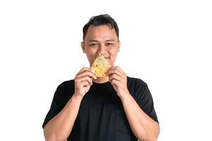 A man in a black shirt smiles while holding a flavorful slice of food photo