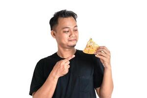 Happy Asian Man Pointing at a Delicious Slice of Pizza in Hand photo