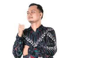 a portrait of an Asian man wearing batik pointing behind him with his thumb photo