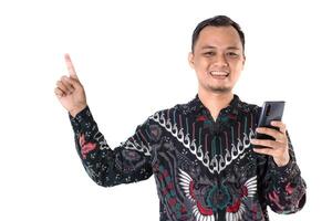 Man in Batik Shirt Pointing While Holding a Smartphone with a Cheerful Smile photo