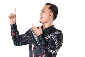 Portrait of a Man in a Batik Shirt Cheerfully Pointing Up photo
