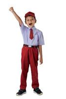 A Indonesian boy in a red school uniform, raising his fist in celebration with a big smile on his face. photo